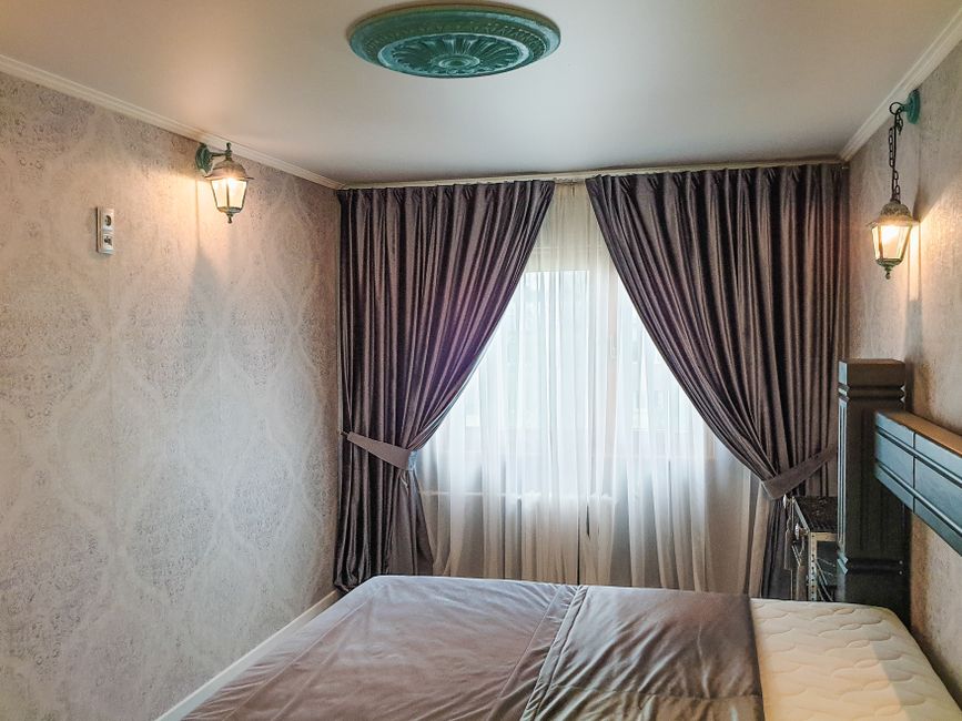 Small rental bedroom with warm lighting and plug-in sconces beside the bed